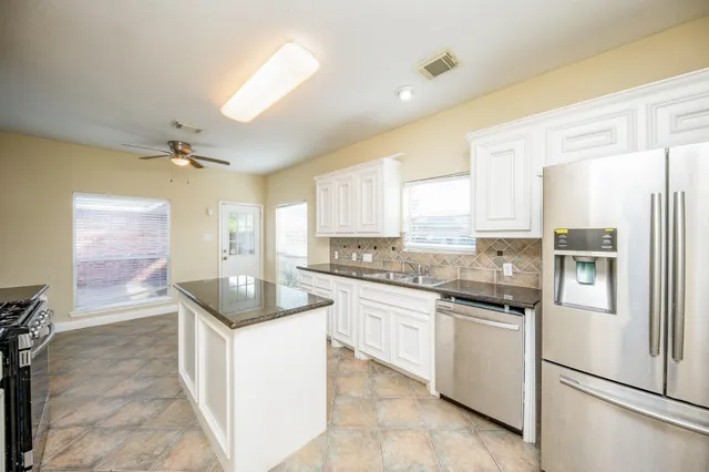 a kitchen with granite countertop a sink stove and refrigerator