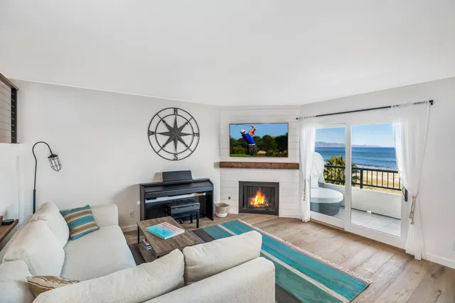 a living room with furniture a rug a fireplace and a window