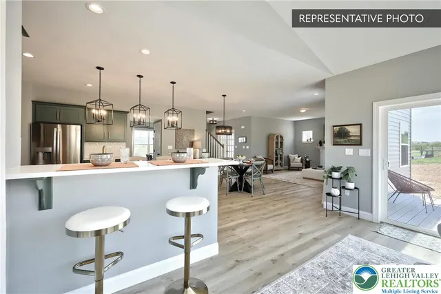 a living room with couches and kitchen view with wooden floor