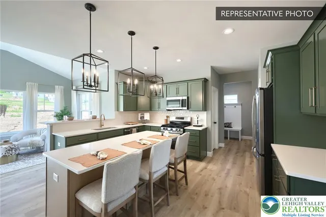 a kitchen with stainless steel appliances granite countertop a sink a stove a refrigerator and chairs