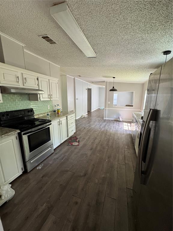 4266 County Road 691 Webster, FL 33597 - Photo 8 of 22 a kitchen with granite countertop a refrigerator and a stove top oven