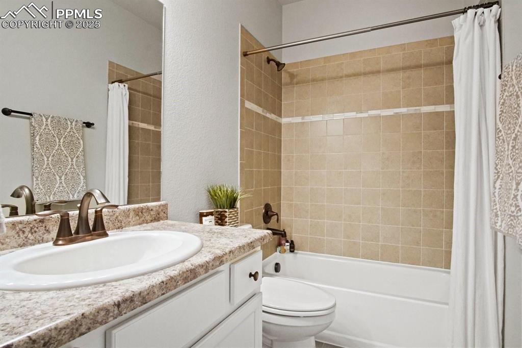 10052 Bracknell Place Peyton, CO 80831 - Photo 19 of 36 a bathroom with a granite countertop sink a toilet and shower