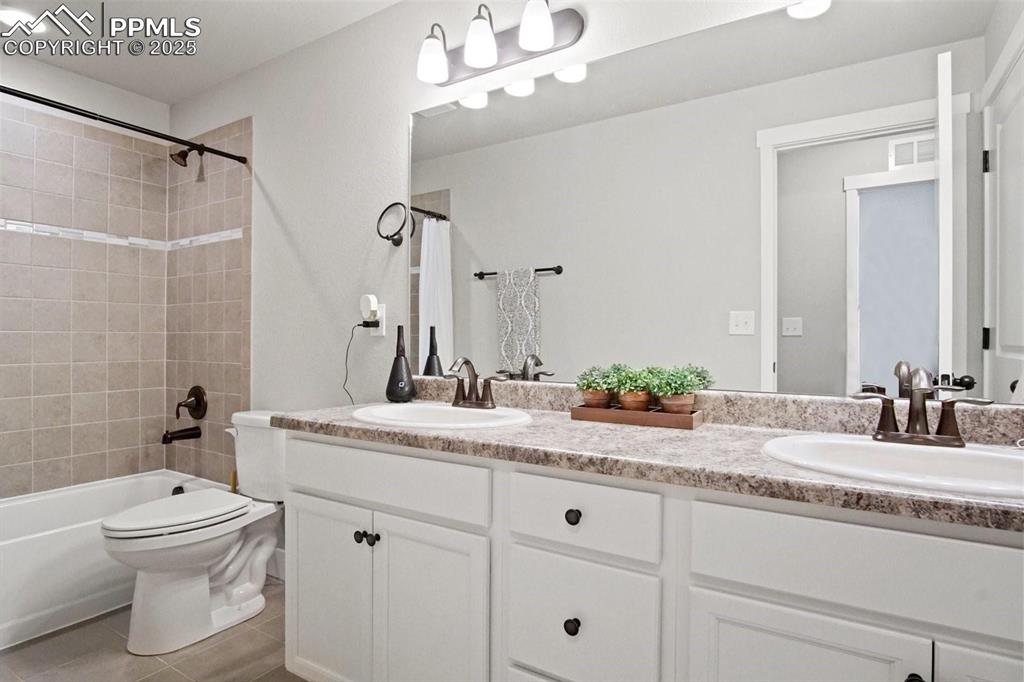 10052 Bracknell Place Peyton, CO 80831 - Photo 28 of 36 a bathroom with a granite countertop sink a toilet a mirror and shower
