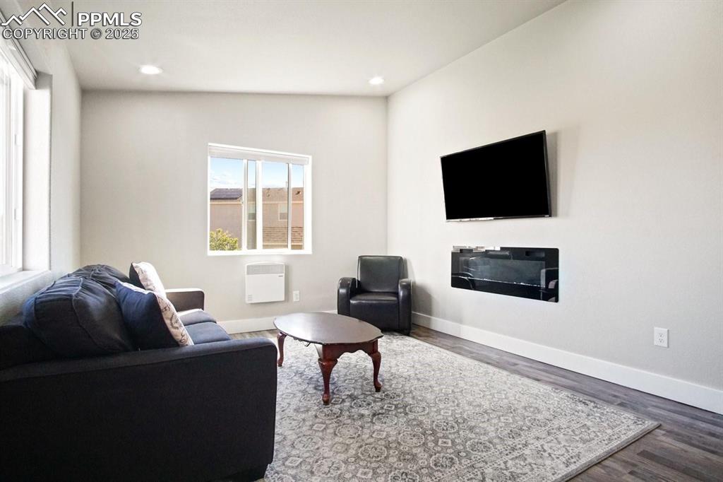 10052 Bracknell Place Peyton, CO 80831 - Photo 32 of 36 a living room with furniture a flat screen tv and a fireplace