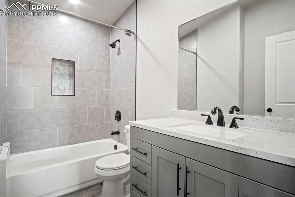 10052 Bracknell Place Peyton, CO 80831 - Photo 35 of 36 a bathroom with a granite countertop sink a toilet a mirror and shower