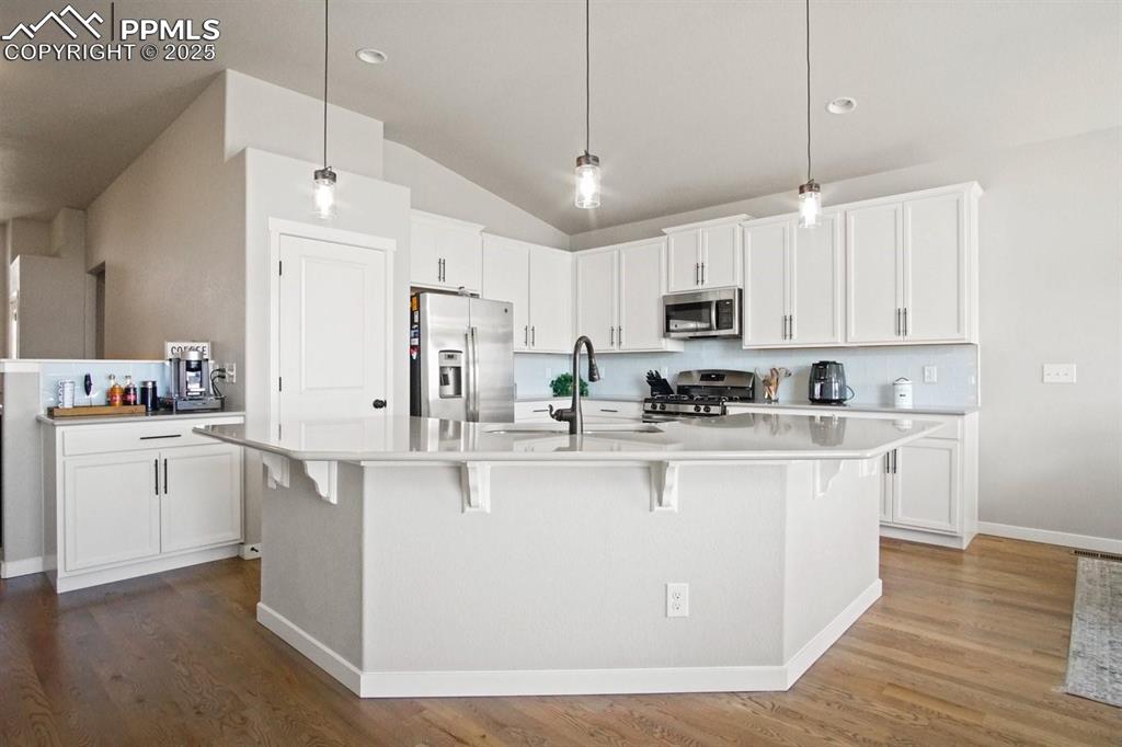 10052 Bracknell Place Peyton, CO 80831 - Photo 9 of 36 a kitchen with stainless steel appliances granite countertop a refrigerator a stove top oven a sink dishwasher and white cabinets with wooden floor