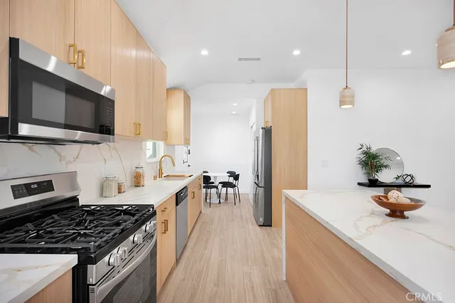 a kitchen with stainless steel appliances a stove a sink and white cabinets