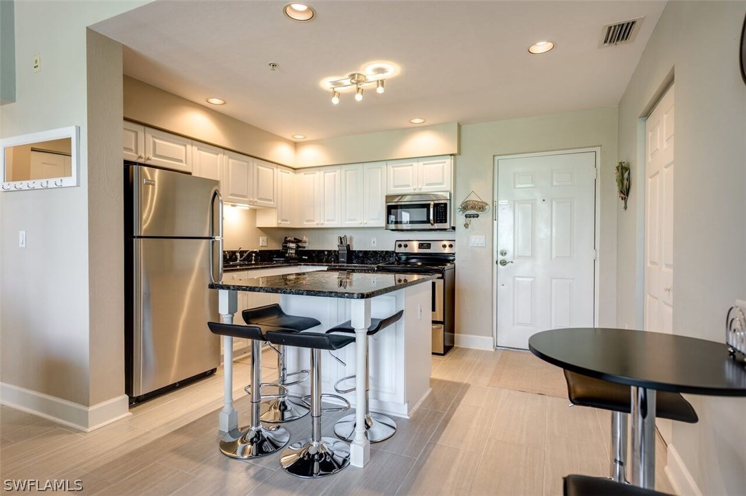 2060 Matecumbe Key Road, Unit 2207 Punta Gorda, FL 33955 - Photo 2 of 21 a kitchen with kitchen island granite countertop stainless steel appliances a refrigerator a stove a sink a dining table and chairs