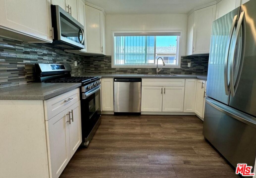 2040 South Sherbourne Drive, Unit 4 Los Angeles, CA 90034 - Photo 13 of 14 a kitchen with granite countertop a sink cabinets stainless steel appliances and a window