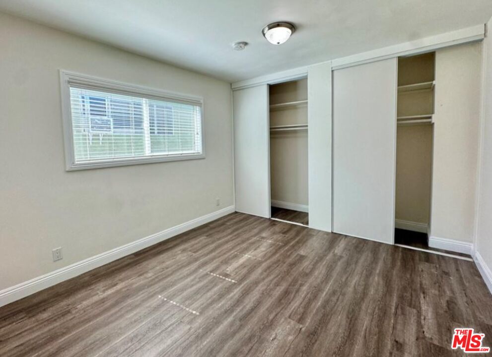 2040 South Sherbourne Drive, Unit 4 Los Angeles, CA 90034 - Photo 7 of 14 an empty room with wooden floor closet and windows