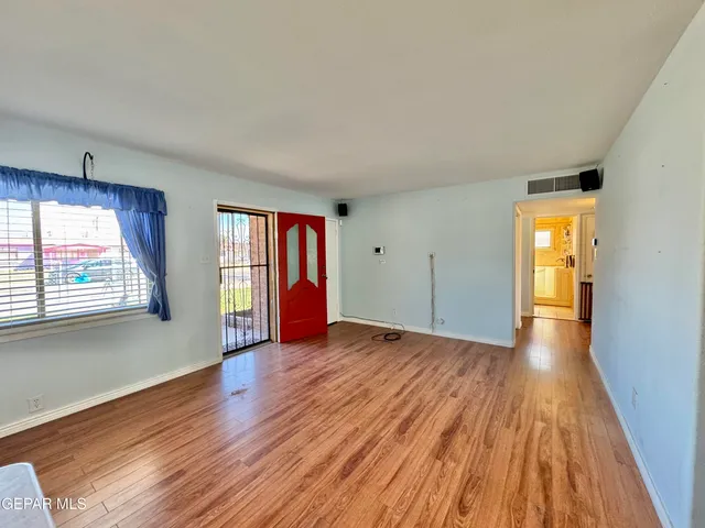 an empty room with wooden floor and windows