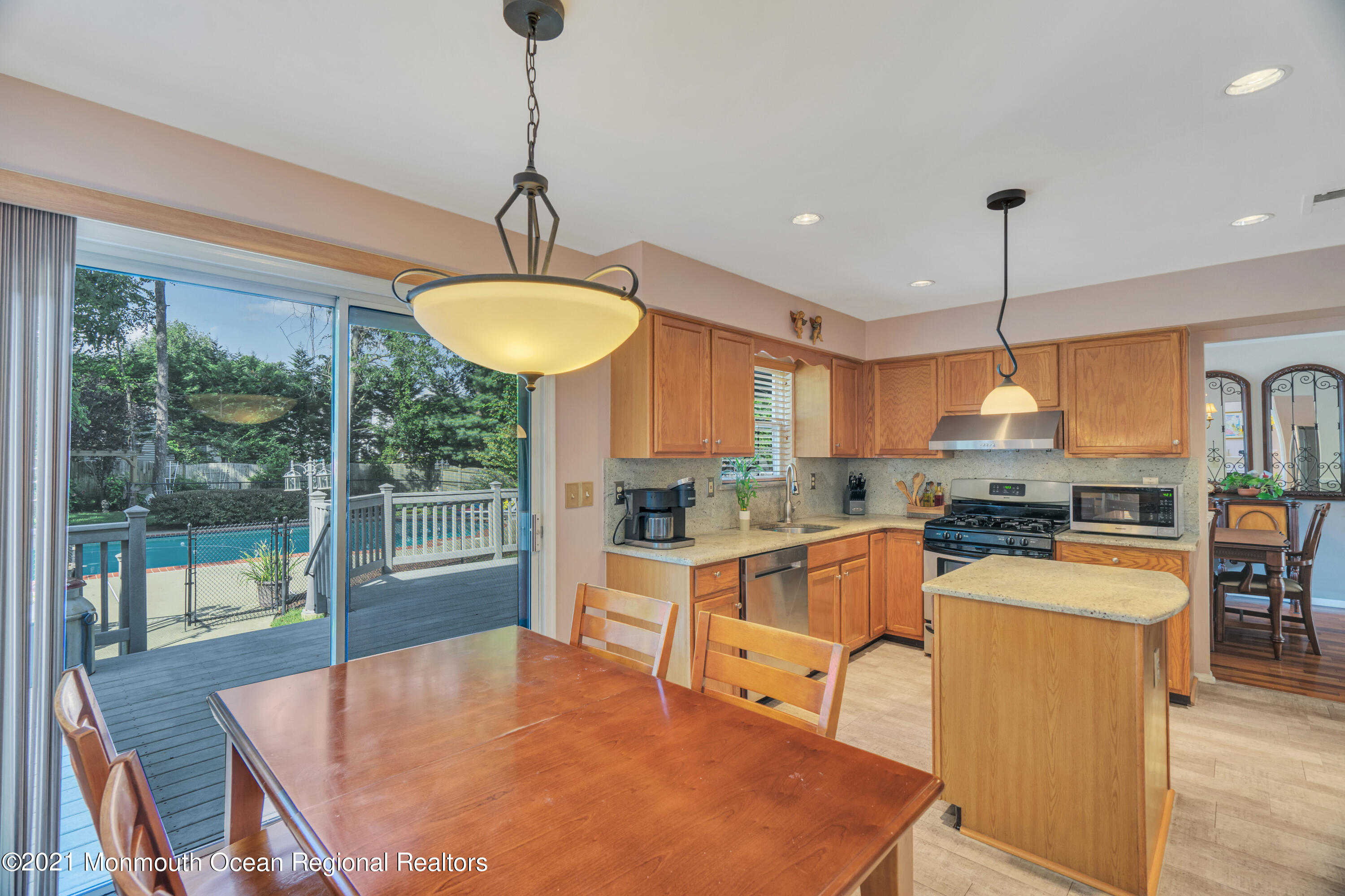 7 Sun Hollow Road Howell, NJ 07731 - Photo 11 of 31 a kitchen with stainless steel appliances granite countertop a stove top oven a dining table and chairs a refrigerator with wooden floor