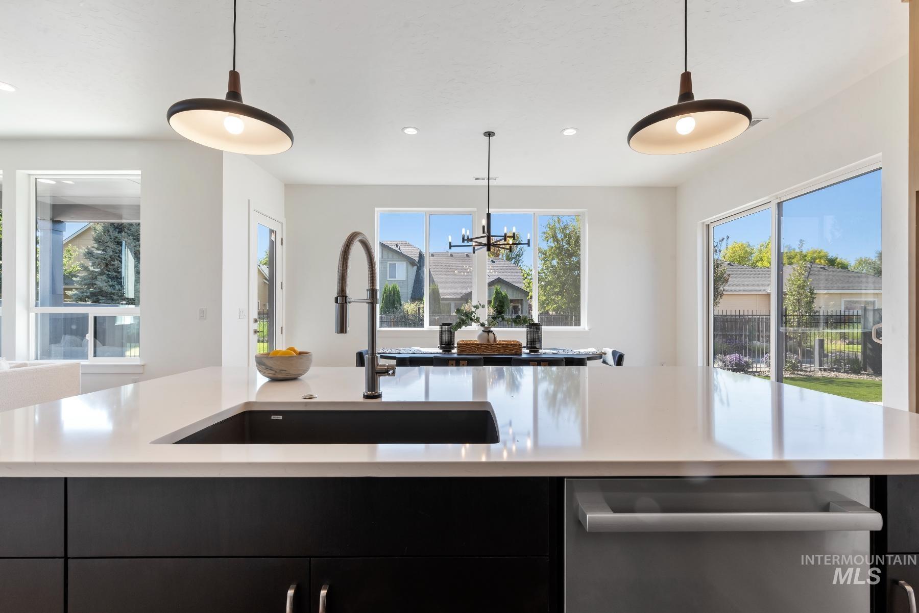 1319 West Malbar Street Meridian, ID 83646 - Photo 11 of 31 Kitchen with dark cabinets, dishwasher, decorative light fixtures, light stone countertops, and recessed lighting