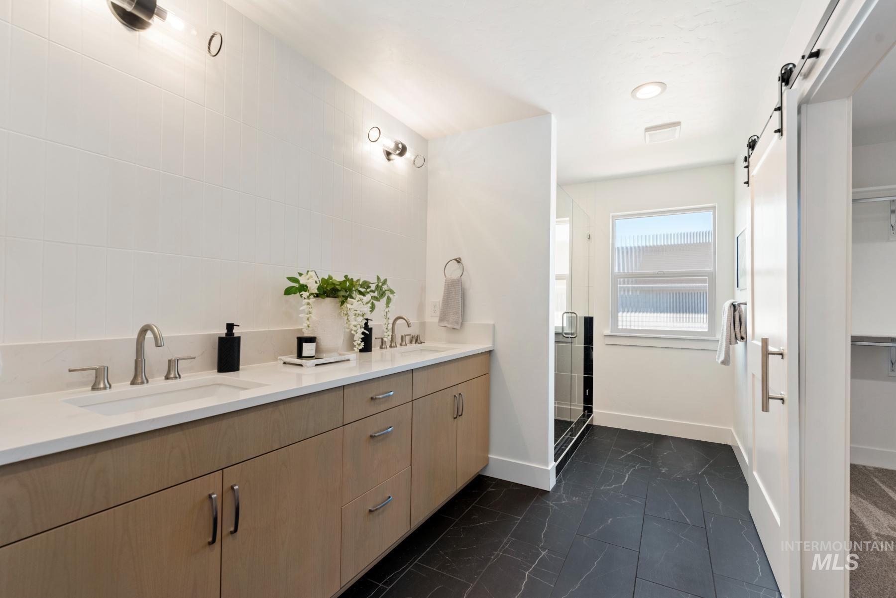 1319 West Malbar Street Meridian, ID 83646 - Photo 20 of 31 Bathroom with double vanity, a stall shower, a walk in closet, and dark marble finish flooring