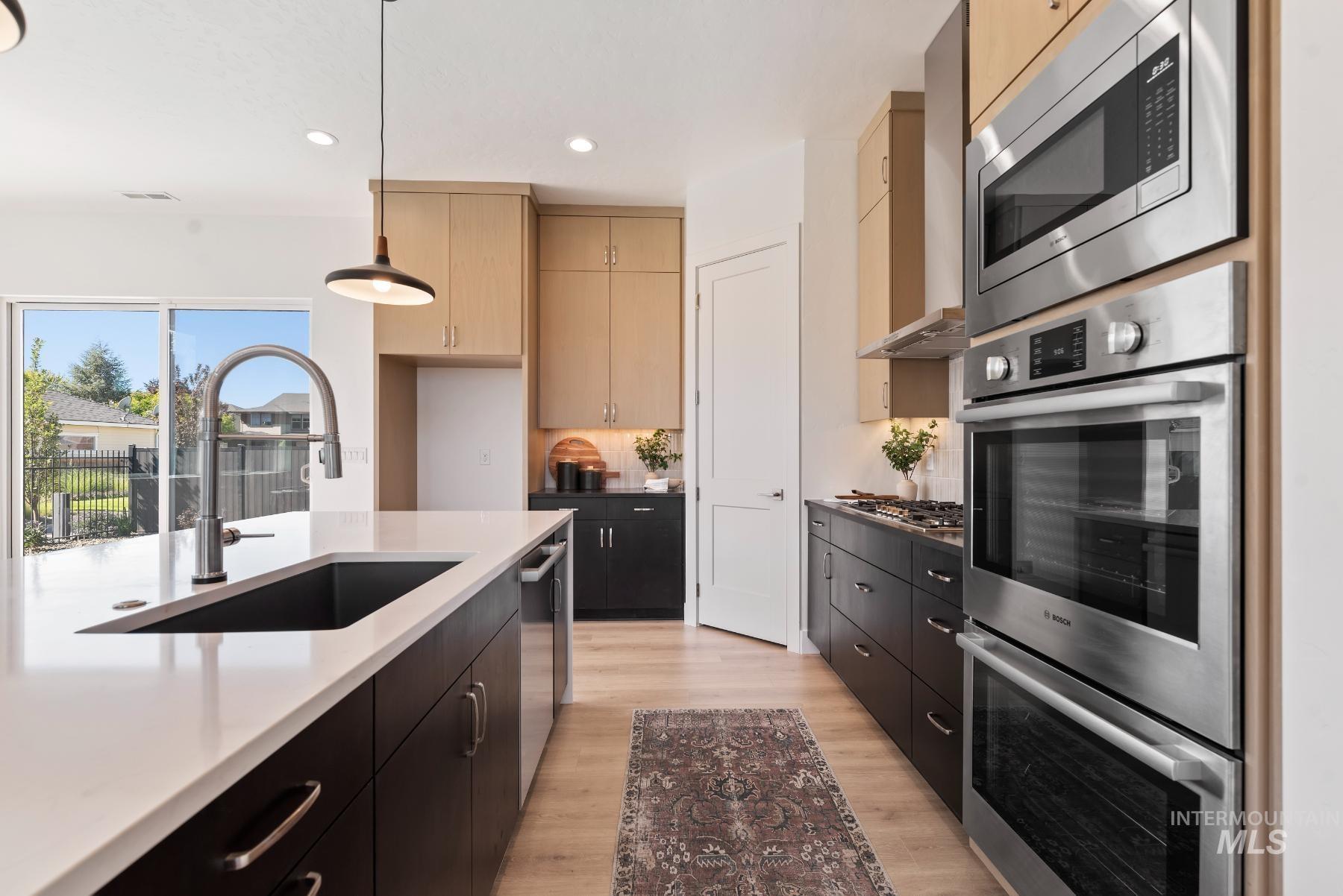 1319 West Malbar Street Meridian, ID 83646 - Photo 10 of 31 Kitchen featuring dark cabinetry, appliances with stainless steel finishes, light wood finished floors, recessed lighting, and decorative light fixtures