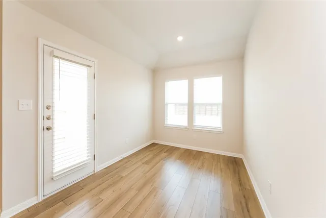 an empty room with wooden floor and windows