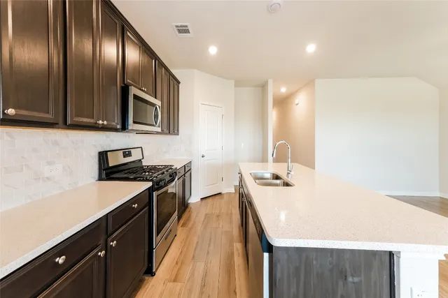 a kitchen with stainless steel appliances a sink stove and cabinets