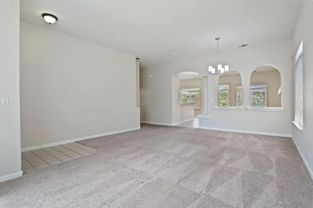 an empty room with chandelier fan and windows