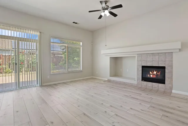 a view of an empty room with wooden floor fireplace and a window