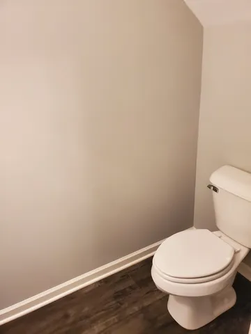 a white toilet sitting next to a white wall