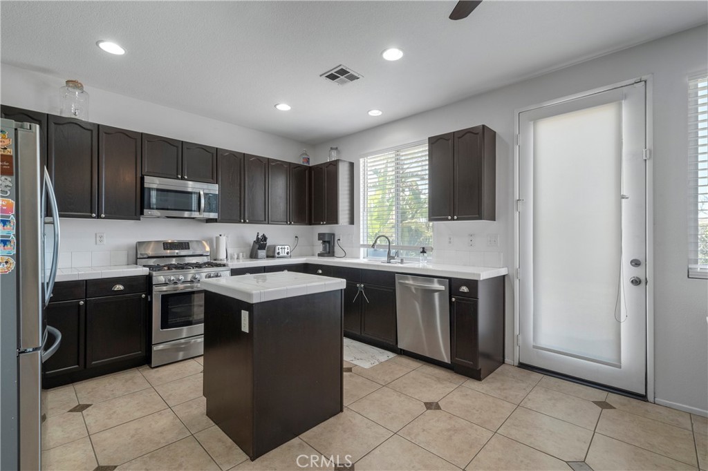 7441 Clementine Drive Eastvale, CA 92880 - Photo 16 of 39 a kitchen with stainless steel appliances granite countertop a refrigerator and a stove top oven