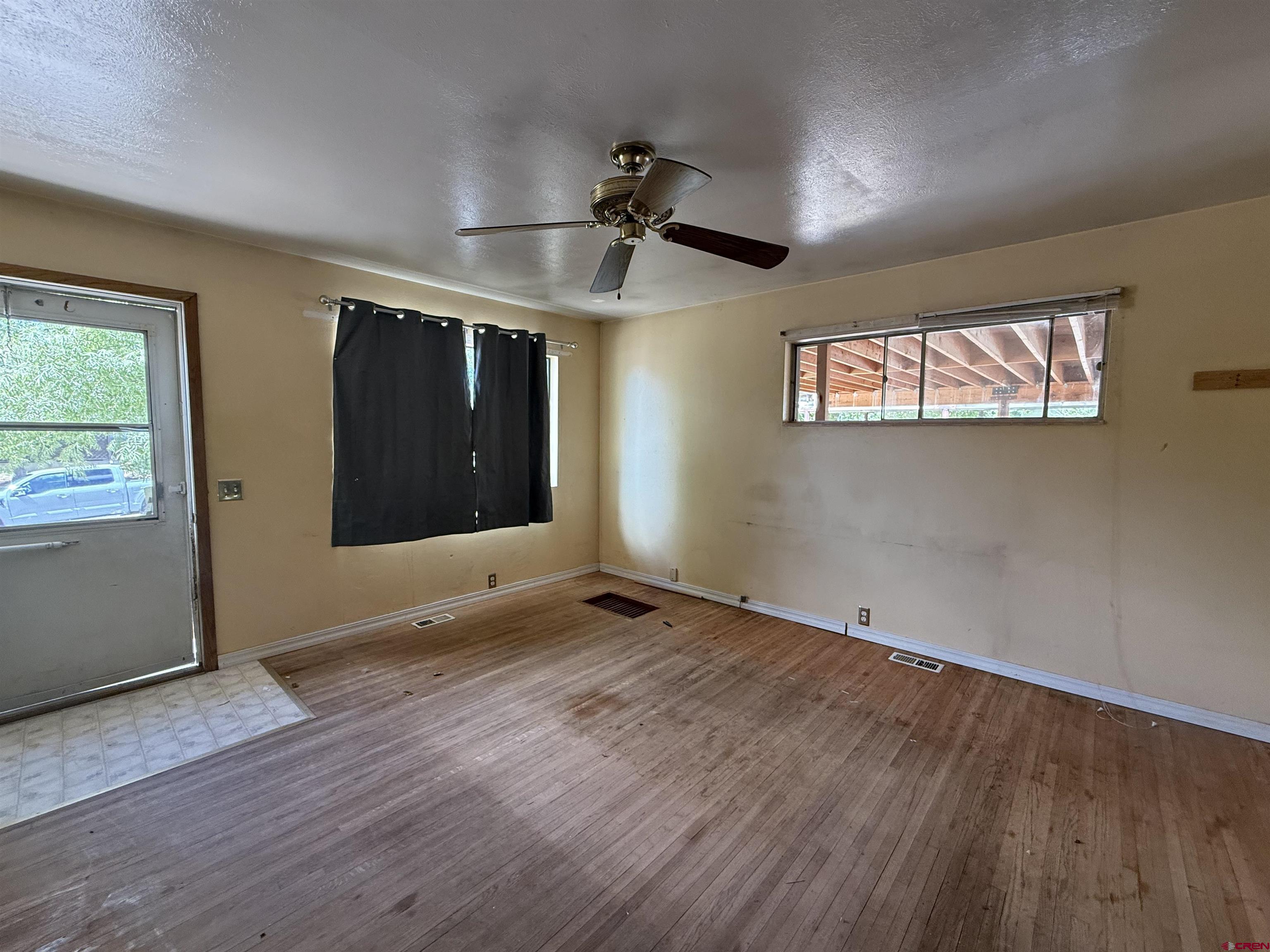 418 South Valley Road Cortez, CO 81321 - Photo 6 of 32 an empty room with wooden floor a ceiling fan and windows