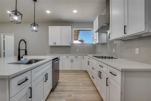 a kitchen with white cabinets stove and sink