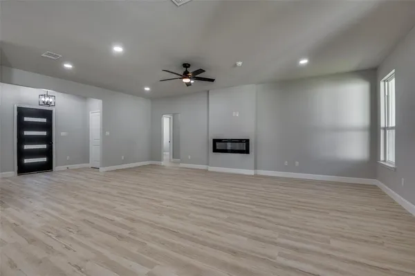 an empty room with windows and ceiling fan