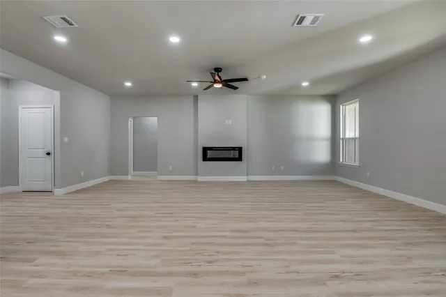 a large kitchen with kitchen island a stove a sink a refrigerator and a fireplace with wooden floor