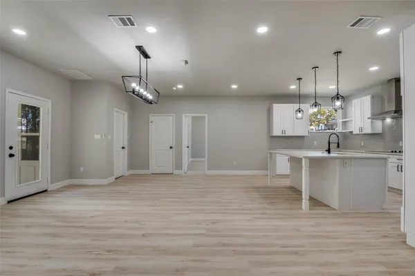 a view of kitchen with kitchen island stainless steel appliances sink cabinets and wooden floor