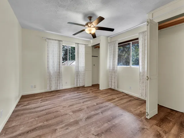 a view of empty room with wooden floor and fan