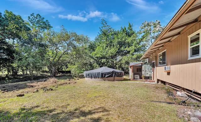 a backyard of a house with table and chairs under an umbrella