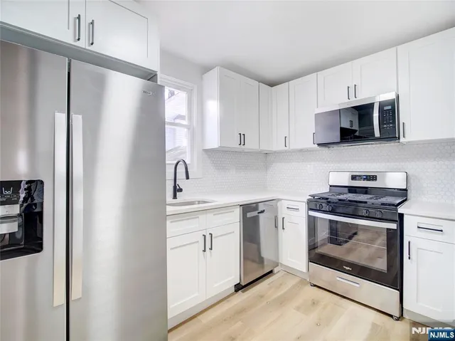 a kitchen with stainless steel appliances granite countertop a stove a refrigerator and a sink