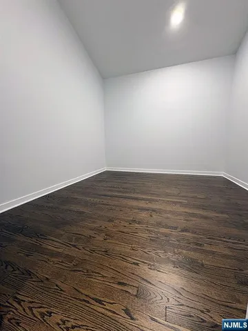 an empty room with wooden floor closet and windows