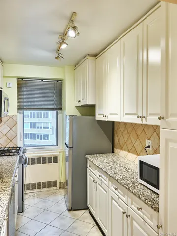 a kitchen with stainless steel appliances granite countertop a refrigerator a stove and a sink with wooden cabinets