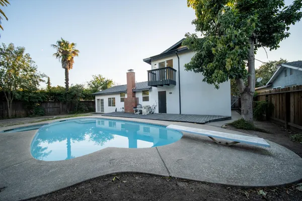 a view of a house with pool fire pit and a trees
