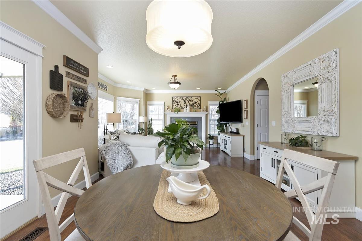 14111 Towers Drive Caldwell, ID 83607 - Photo 11 of 50 Dining room featuring ornamental molding, a fireplace, arched walkways, and dark wood-style flooring
