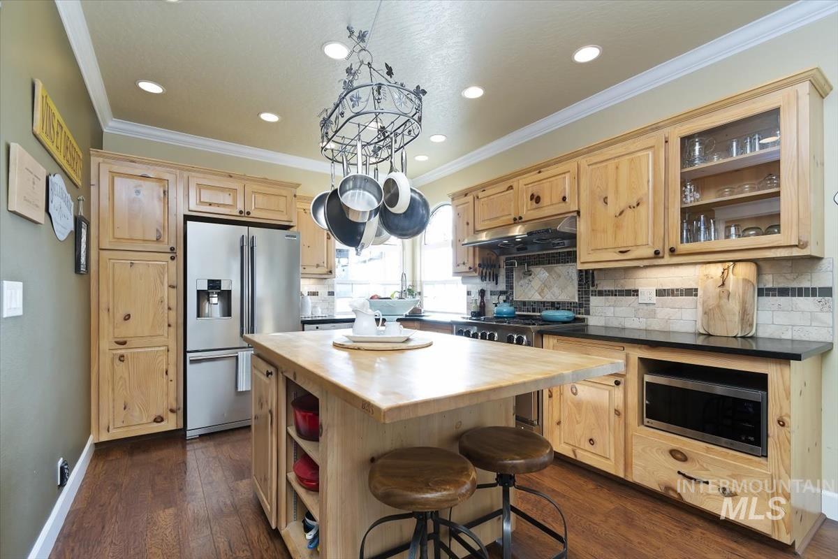 14111 Towers Drive Caldwell, ID 83607 - Photo 14 of 50 Kitchen featuring light brown cabinetry, a kitchen bar, a center island, crown molding, and recessed lighting