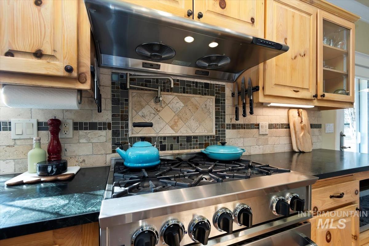 14111 Towers Drive Caldwell, ID 83607 - Photo 15 of 50 Kitchen featuring under cabinet range hood, glass insert cabinets, gas stove, light brown cabinets, and backsplash