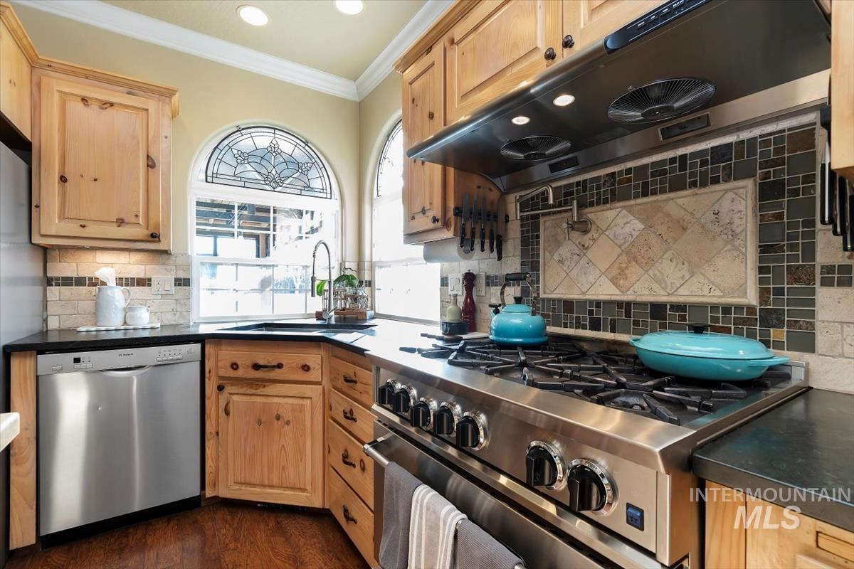 14111 Towers Drive Caldwell, ID 83607 - Photo 17 of 50 Kitchen featuring under cabinet range hood, stainless steel appliances, ornamental molding, dark countertops, and dark wood-type flooring