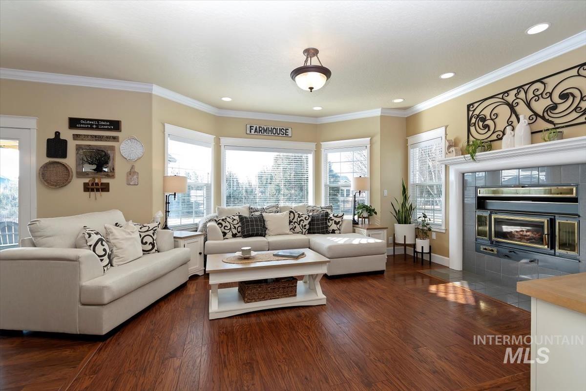 14111 Towers Drive Caldwell, ID 83607 - Photo 6 of 50 Living room with dark wood-style flooring, a tiled fireplace, ornamental molding, and recessed lighting