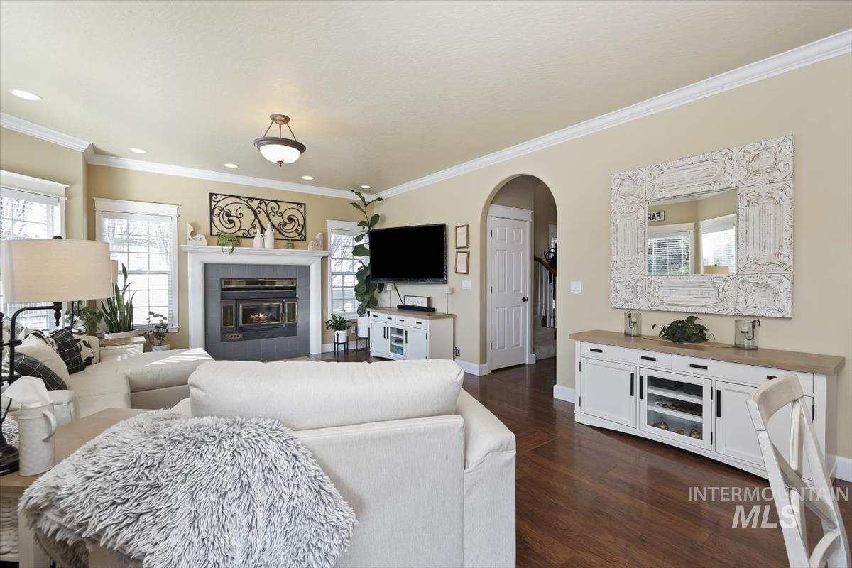 14111 Towers Drive Caldwell, ID 83607 - Photo 10 of 50 Living area with arched walkways, a tiled fireplace, dark wood finished floors, and ornamental molding