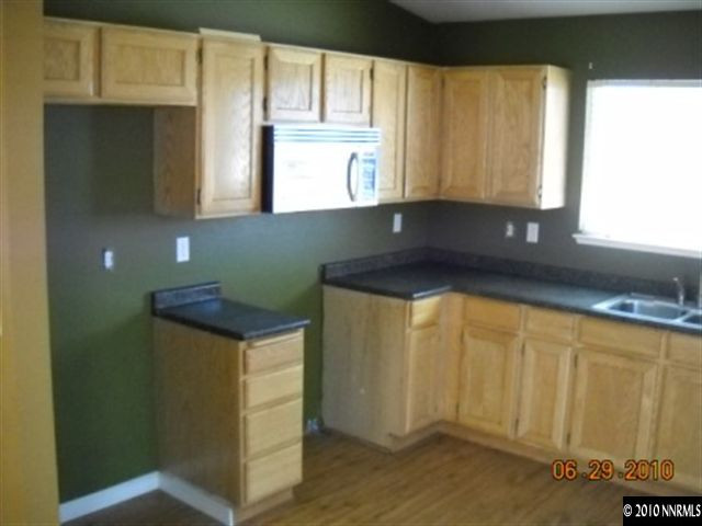 4568 Goodwin Road Sparks, NV 89436 - Photo 4 of 6 a kitchen with granite countertop white cabinets and window