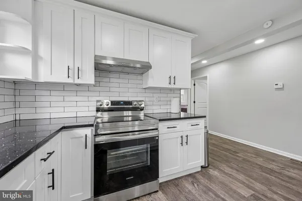 a kitchen with granite countertop white cabinets and stainless steel appliances
