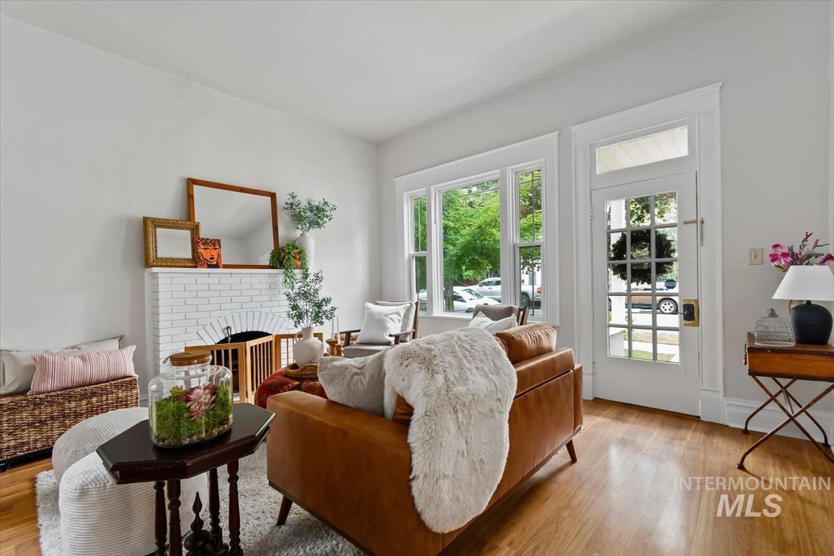 910 North 16th Street Boise, ID 83702 - Photo 6 of 47 Living area featuring wood-finish flooring, a white brick fireplace with a dark arch, and multiple windows