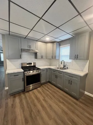 a kitchen with granite countertop a sink cabinets and stainless steel appliances