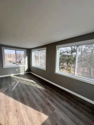 a view of an empty room with a window and wooden floor