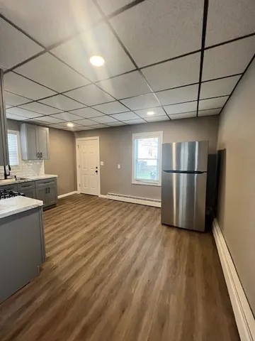 a view of empty room with wooden floor and kitchen appliances