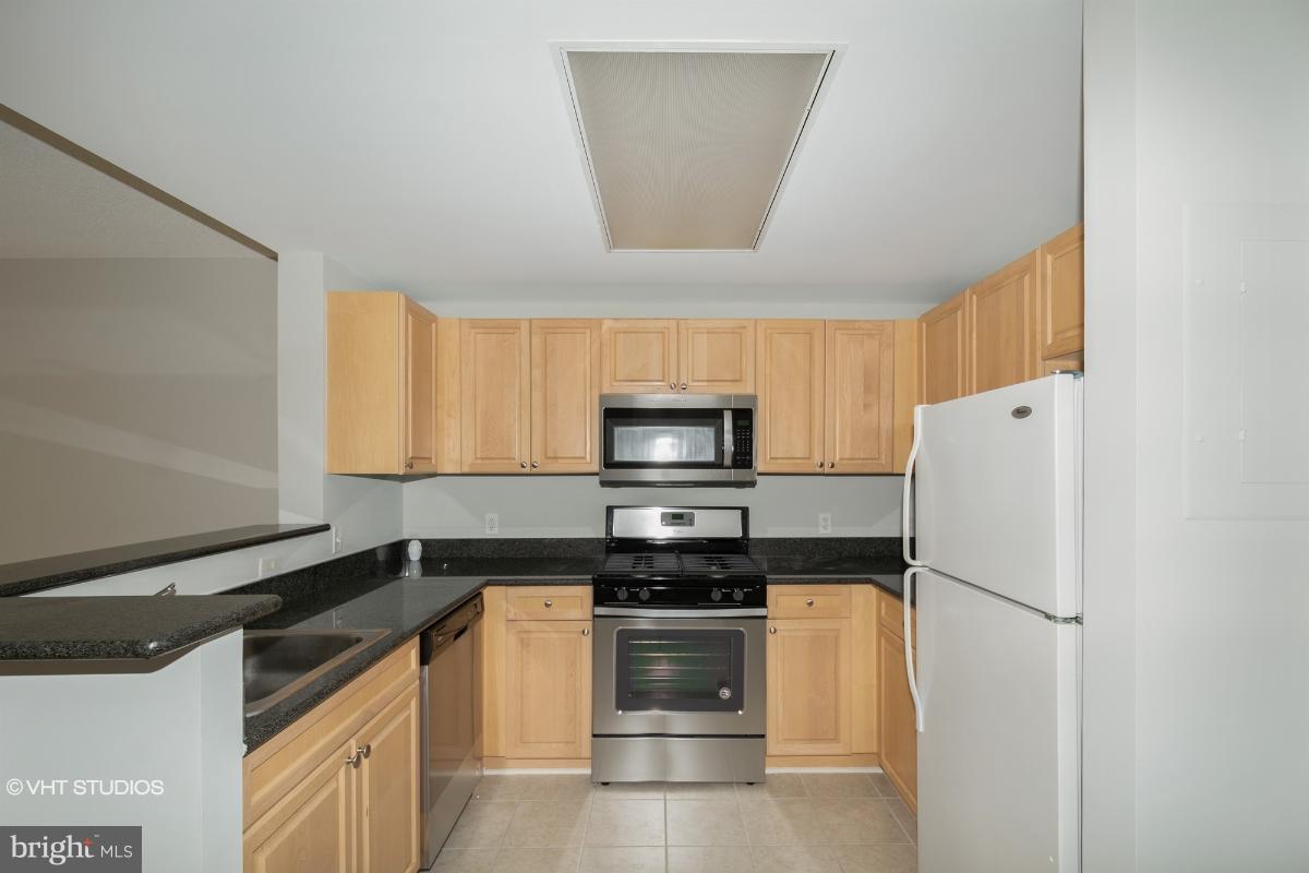 2726 Gallows Road, Unit 1202 Vienna, VA 22180 - Photo 6 of 24 a kitchen with a refrigerator and a stove top oven