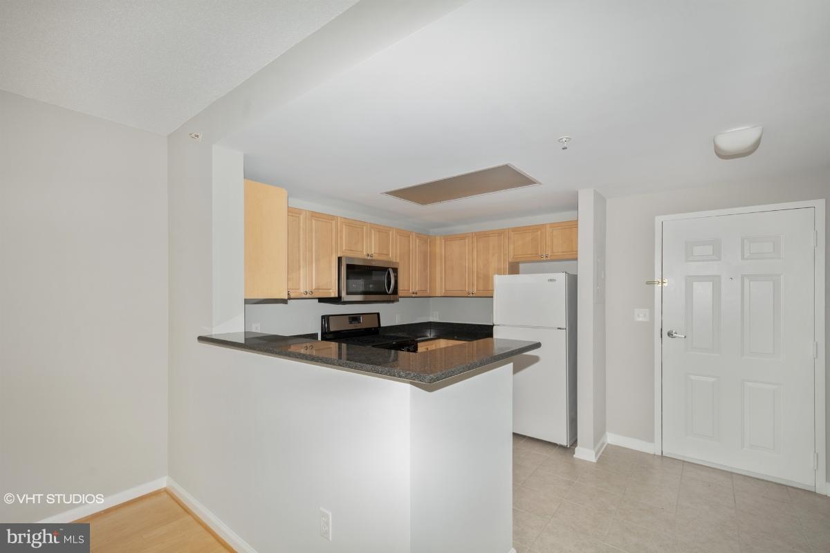 2726 Gallows Road, Unit 1202 Vienna, VA 22180 - Photo 9 of 24 a kitchen with stainless steel appliances a refrigerator a stove a sink and a white cabinets